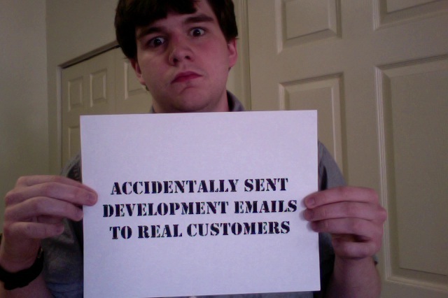 Me holding a sign that reads "Accidentally sent development emails to real customers"